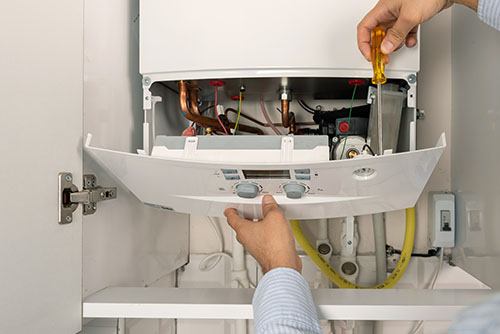 HVAC technician repairing an indoor boiler in Orem